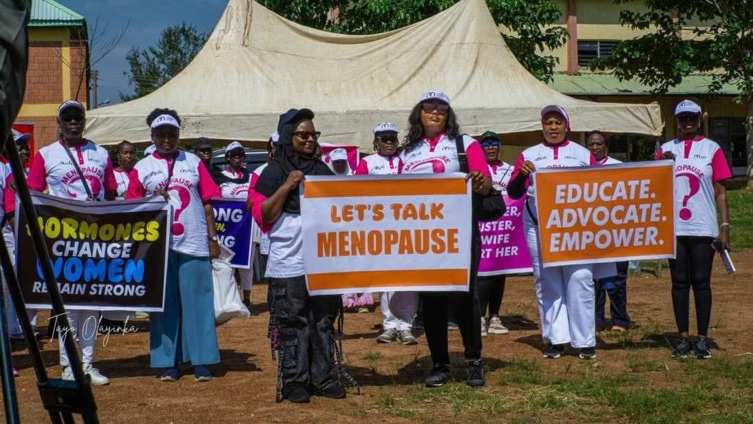 Walkers holding "Let's talk menopause" and "Educate. Advocate. Empower." placards
