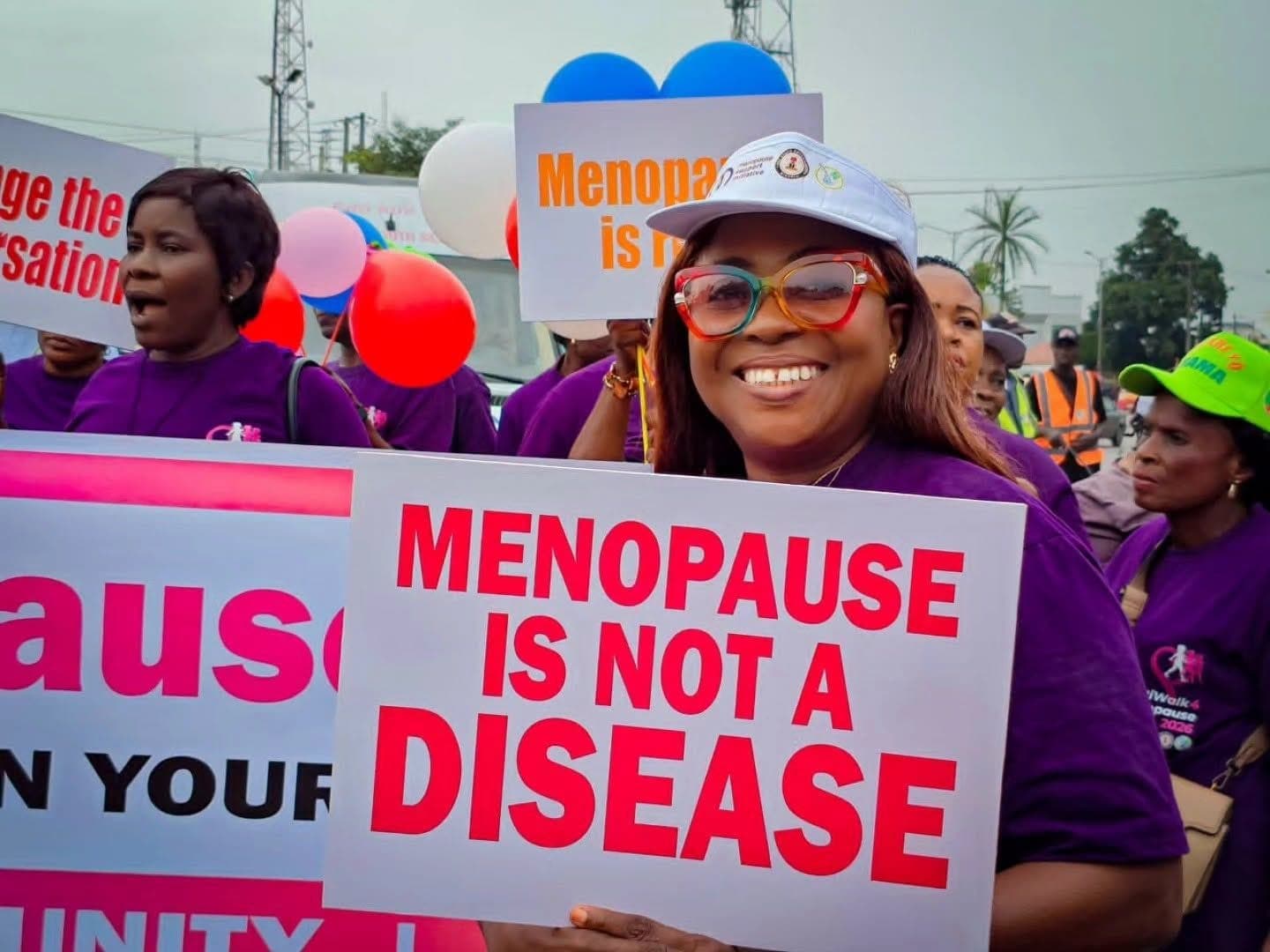 A MenoClub member holding a 'Menopause is not a disease' placard at the walk
